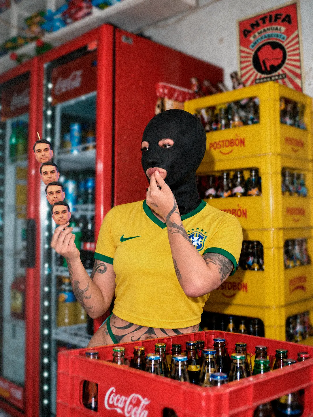 Fetish 2 (Scatology) — performance still: a masked figure in a cropped Brazil shirt holds a skewer of photographic cutouts inside a bodega